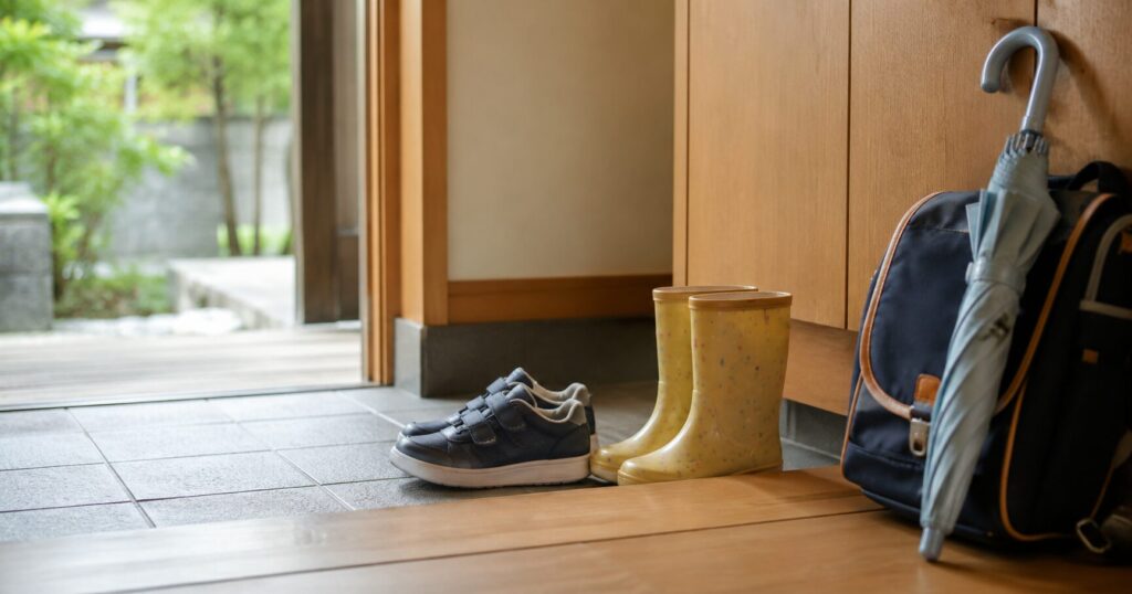 玄関に子どものスニーカーとレインブーツを並べた様子
