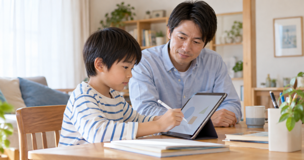 机でタブレットに取り組む小学生と隣で学習を見守る保護者